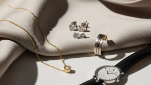 Elegant quiet luxury gold jewelry pieces laid flat on marble surface showing minimalist design and premium craftsmanship