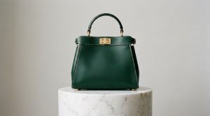 Luxury top handle leather bag displayed on a marble pedestal with gold hardware.